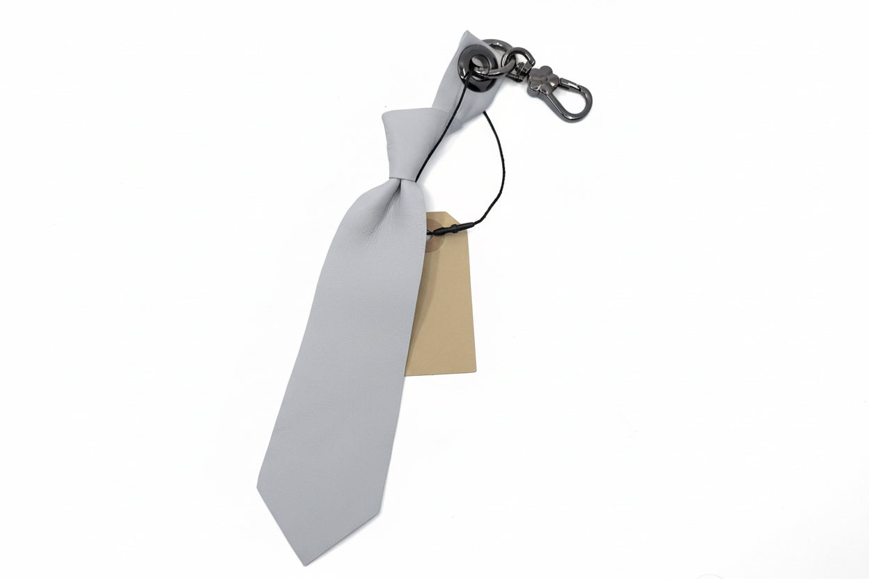 Gray tie-shaped keychain with a metal clasp on a light gray background