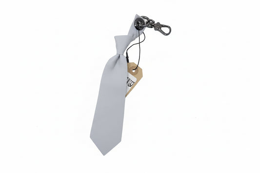 White tie-shaped keychain with a metal clip on a white background